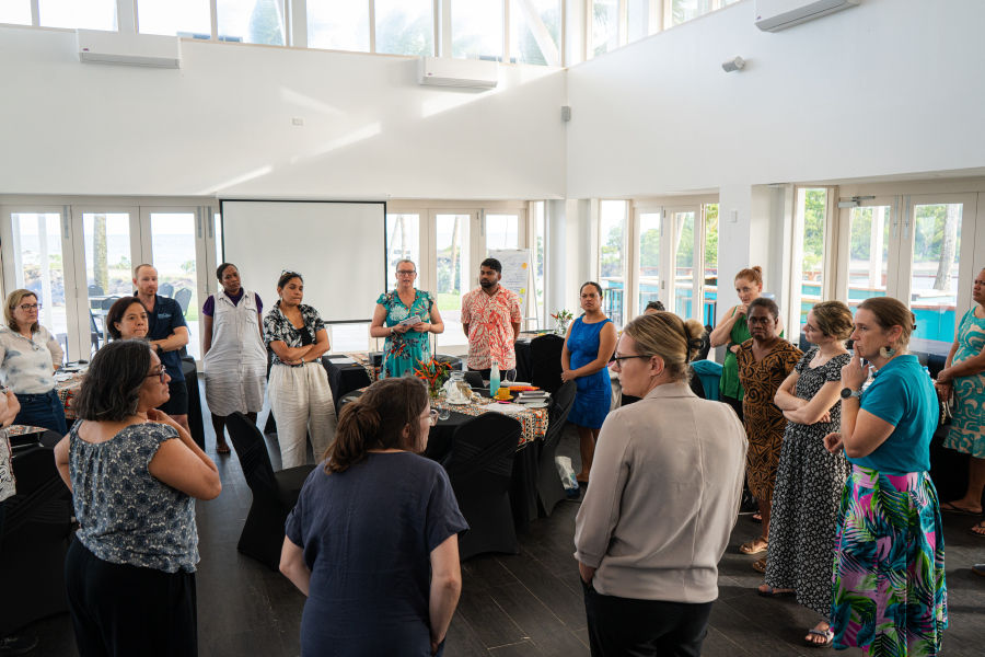 Workshop participants stand in a circle listening to a speaker.