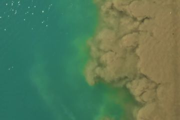 An aerial view of water pollution from flooding mixing with clean water.